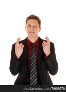 A business man standing in a suit and tie crossing his fingers, making asign of luck, isolated for white background.