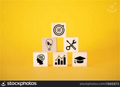 A business or economic growth concept with icons and goals on wooden cubes on a yellow background. Goals that are worth paying attention to.. A business or economic growth concept with icons and goals on wooden cubes on a yellow background.