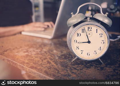 A business owner using laptop and working on time with clock on the table