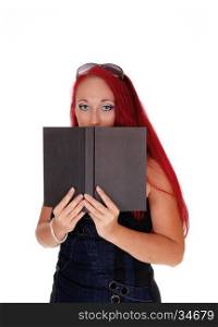 A business woman holding a book on her face, standingwith long red hair isolated for white background.