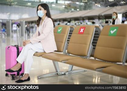A business woman is wearing protective mask in International airport, travel under Covid-19 pandemic, safety travels, social distancing protocol, New normal travel concept.. A business woman is wearing protective mask in International airport, travel under Covid-19 pandemic, safety travels, social distancing protocol, New normal travel concept