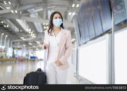 A business woman is wearing protective mask in International airport, travel under Covid-19 pandemic, safety travels, social distancing protocol, New normal travel concept.. A business woman is wearing protective mask in International airport, travel under Covid-19 pandemic, safety travels, social distancing protocol, New normal travel concept