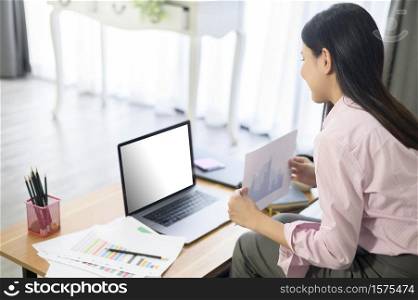 A business woman is working with laptop mock up screen, analyzing business plan in home office.