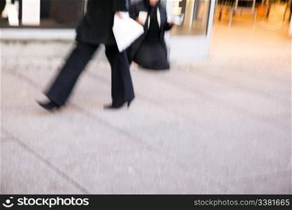 A business woman quickly walking. Motion blur is used to create the photograph.