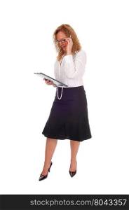 A business woman standing in a black skirt white blouse holdingher clipboard, looking at, isolated for white background.