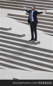 A businessman business man successful celebrating or depressed standing arms outstretched on the steps in a city