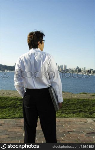 A businessman carrying a laptop relaxing at a park