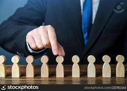 A businessman chooses a person from a row. Recruiting. Headhunter HR. Study and selection of candidates. Find the right candidate for the job. Management and Recruitment. Hire new workers