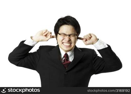 A businessman covering his ears with his fingers