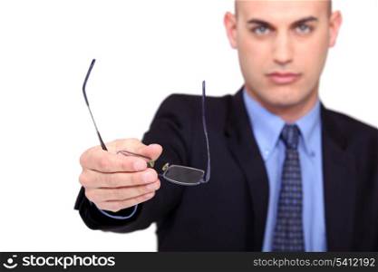A businessman handing his glasses over.