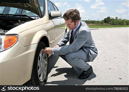 A businessman has a flat tire on the road. He&rsquo;s getting ready to change it.