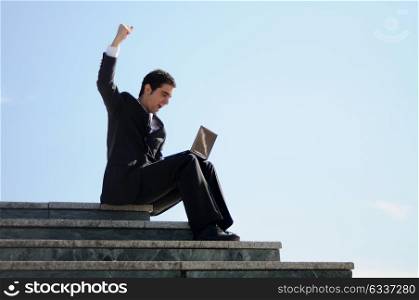 A businessman holding a laptop computer with his arm up