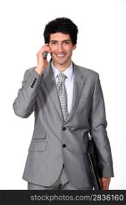 A businessman holding a phone and a laptop.