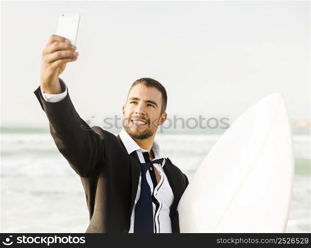 A Businessman holding is surfboard after a long day of work and making a selfie