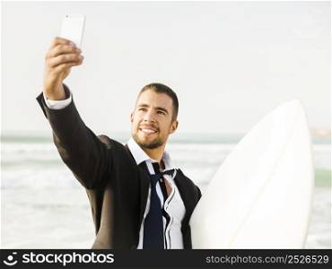 A Businessman holding is surfboard after a long day of work and making a selfie