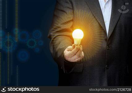 A businessman holds an electric lamp in his hand on a dark blue background. Concept of new ideas in business, innovation