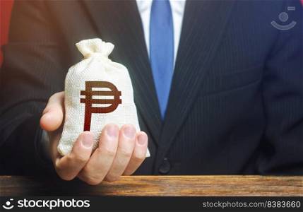 A businessman holds in his hand a philippine peso money bag. nvestments, financing. Stimulating economic recovery. Providing business with preferential loans and support during the economic crisis. I