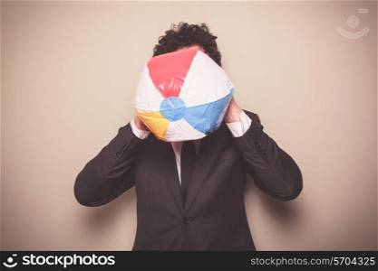A businessman is blowing up a multi colored beach ball