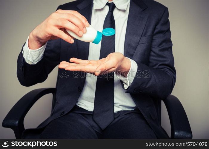 A businessman is squeezing a tube of sun screen