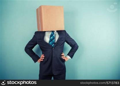 A businessman is standing with a cardboard box on his head