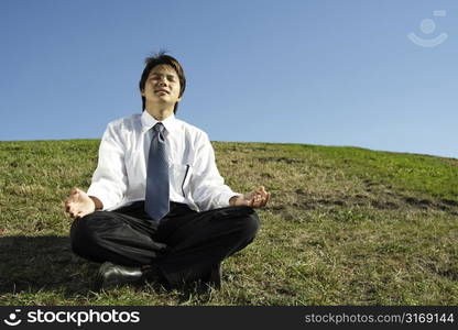 A businessman meditating in a park