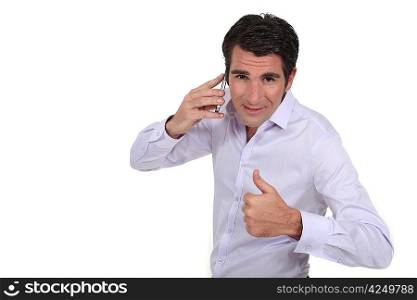 A businessman over the phone giving the thumb up.
