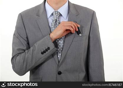 A businessman putting his Usb key in his pocket.