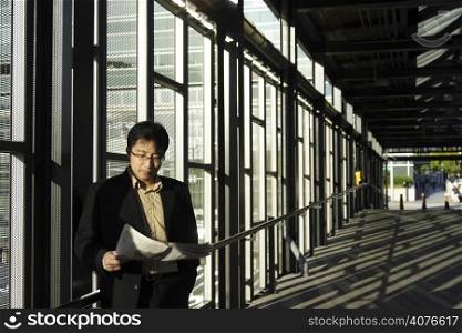 A businessman reading a financial newspaper at the train station