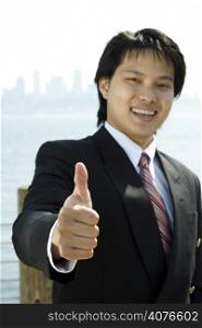 A businessman smiling with his thumbs up (focus on the thumb)