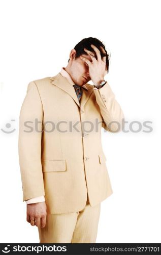A businessman standing in a beige suit, holding he hand over his face,is ashamed over his bankrupts, over white background.