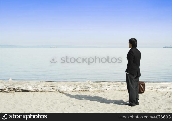 A businessman standing on the beach alone enjoying the view