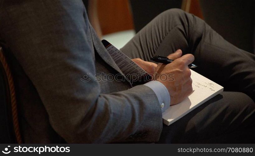 A businessman takes notes at a conference