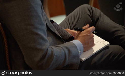 A businessman takes notes at a conference