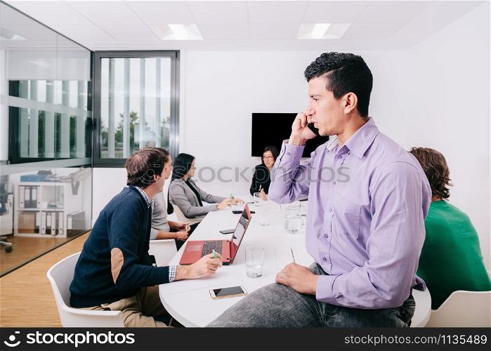 A businessman talking on cell phone sitting at the office table