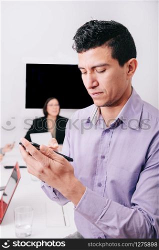 A businessman using his cellphone sitting at the office table