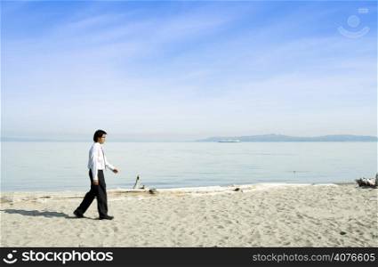 A businessman walking along the beach alone