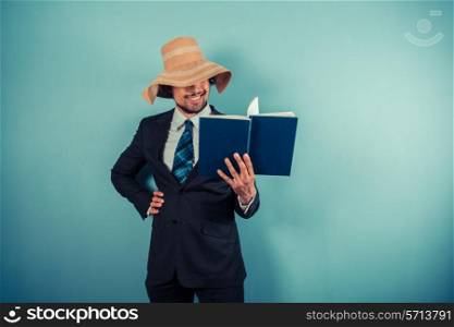 A businessman wearing a beach hat is reading a book