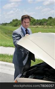 A businessman whose car has broken down, checking under the hood.