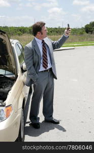 A businessman whose care has broken down in a remote location checking for phone signal.