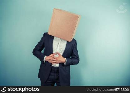 A businessman with a cardboard box on his head is having stomach pains