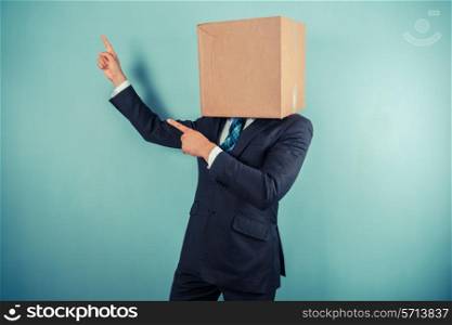 A businessman with a cardboard box on his head is pointing
