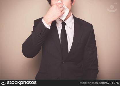 A businessman with a cold is blowing his nose