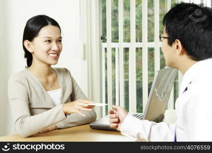A businesswoman handing out a business card to a businessman