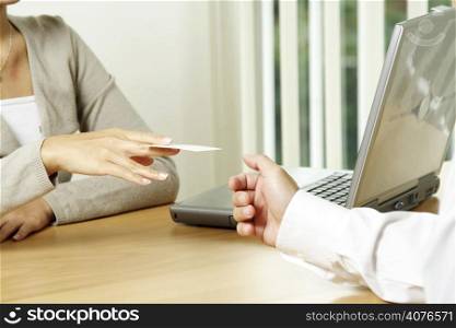A businesswoman handing out a business card to a businessman