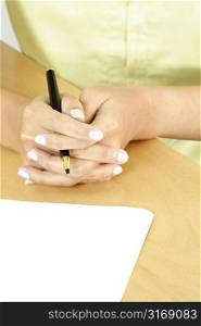 A businesswoman holding a pen ready to write on a piece of blank paper
