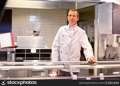 A butcher standing at a fresh meat counter in a grocery store