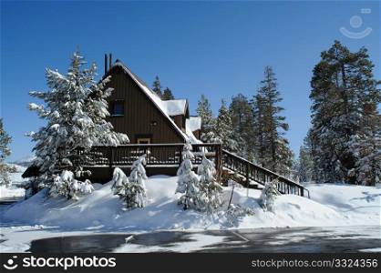 A cabin in the mountais covered with snow after a winter storm.