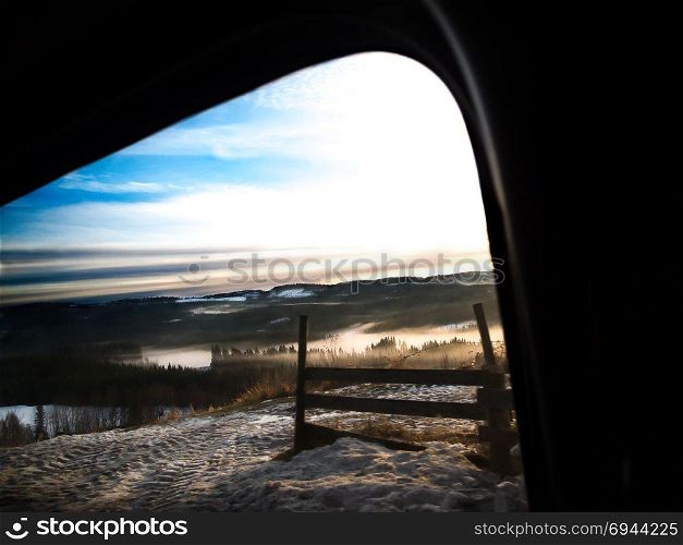 A calm winter morning in the countryside, with copyspace.. High view over misty sunrise in winter landscape