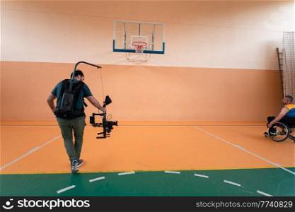 a cameraman with professional equipment records a match of the national team in a wheelchair playing a match in the arena. High quality photo. Selective focus . a cameraman with professional equipment records a match of the national team in a wheelchair playing a match in the arena