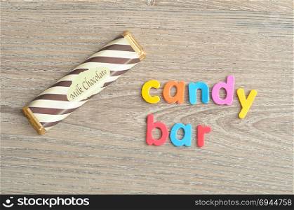 A candy bar with a wrapper isolated on a wooden background with the word candy bar